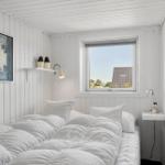 A bedroom with a white bed, wall art, and window view of a roof.