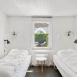 Two beds with white bedding, window overlooking garden, wall lamps and artwork.