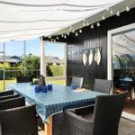 Terrace with table, chairs, and sun canopy. Background: garden and house.
