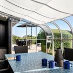 Terrace with table, chairs, and sun cover. View of garden and neighboring houses.