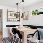 Dining area with wooden table, bench, and pendant lights on white walls.