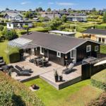 Modern villa with large wooden terrace, garden, and barbecue area. View of residential area.
