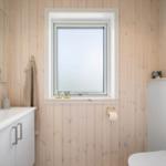 Badezimmer mit Holzwand, Waschbecken, Toilette und Fenster