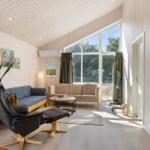 Wohnzimmer mit Sofa, Sessel und großen Fenstern. Holzwände und Boden.