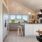 Küche mit Holzwand, Fenster, Arbeitsplatte und Sitzgelegenheit.