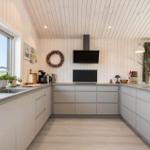 Moderne Küche mit Holzwand und Fenstern. Arbeitsplatte, Schränke und Küchengeräte sichtbar.