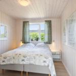 Schlafzimmer mit Bett, Fenster und Holzwänden. An den Wänden hängen Bilder.