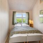 Schlafzimmer mit Bett, Fenster und Holzwandverkleidung.