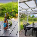Tisch mit Weinflasche und Gläsern im Garten unter Pavillon mit Schaukel.