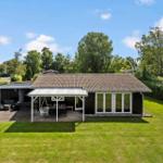 Ein Haus mit Terrasse, Garten und Sitzgelegenheiten unter freiem Himmel.