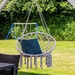 Hängesessel mit Kissen unter Pavillon im Garten mit Spielplatz im Hintergrund.