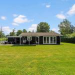 Ein Haus mit Terrasse, Garten und Hängesessel unter blauem Himmel.