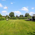 Großer grüner Garten mit Flagge, Terrasse und Sitzgelegenheiten neben dem Haus.