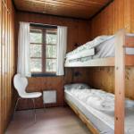 Ein Raum mit Holzwänden, einem Fenster, einer weißen Stuhl und einem Doppelstockbett.