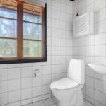Badezimmer mit Toilette, Waschbecken und Fenster mit Blick auf die Natur.