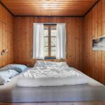 Schlafzimmer mit Holzwandverkleidung, Fenster und Bett.
