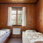 Zwei Betten in einem Zimmer mit Holzwänden und Fenster.