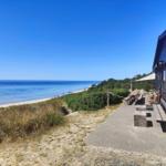 Strandnahe Terrasse mit Sitzgelegenheiten und Blick aufs Meer.