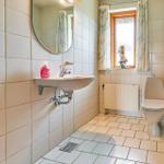 Bathroom with sink, toilet, and window with curtains.