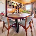 Round dining table with chairs, bookcase, and fireplace in living room.