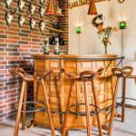 Wooden bar with three stools in front of brick wall with deer heads
