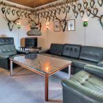 Living room with leather sofa, chairs, and table. Wall decor with deer antlers and skulls.
