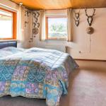 Bedroom with bed, windows, and wall decoration.
