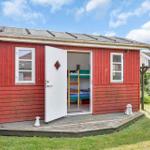 Red wooden house with open door, inside a bunk bed with green mattress.