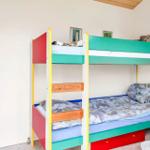 Room with climbing wall and bunk bed with colorful mattresses.