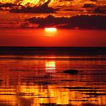 Sunset over the sea with orange sky and reflection on the water surface.