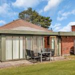 House with terrace, garden, and barbecue area under blue sky.