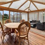 Terrasse mit Holzboden, runden Tisch und Stühlen, Sofa und Teppich.