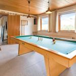 Pool table with green felt, windows, and bookshelf in room.