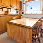 Kitchen with wooden table and chairs, window with curtain and pendant lamps.