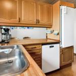 Kitchen with wooden cabinets, sink, refrigerator, and dishwasher.