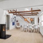 Raum mit Esstisch, Stühlen, Kamin und Holzbalken an der Decke.