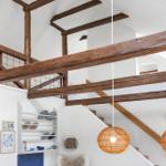 Raum mit Holzbalken, Treppe und hängenden Lampen