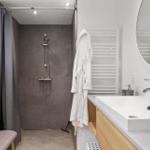 Badezimmer mit Dusche, Waschbecken und Bademantel.