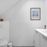 Badezimmer mit Toilette, Waschbecken und Spiegel. Wandbild und Holzdekor.