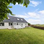 Ein Haus mit Garten und Terrasse unter blauem Himmel.