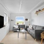 Wohnzimmer mit grauen Sofas, Holzboden und Fenster zum Grasfeld.