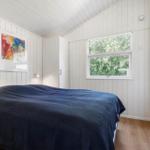 Schlafzimmer mit Bett, Fenster und Wandbild.