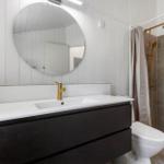Badezimmer mit Waschtisch, Spiegel, Dusche und Toilette.