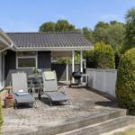 Terrasse mit Liegestühlen, Grill und Tisch. Hinterhof mit Hecken und Zufahrt.
