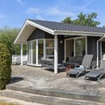Moderne Villa mit Terrasse, Sonnenliegen und grüner Umgebung.