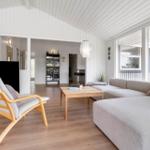Wohnzimmer mit Sofa, Holzstuhl und Fernseher. Holzfußboden und weiße Wände.