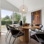 Esszimmer mit Holztisch, schwarzen Stühlen und großem Fensterblick auf Garten