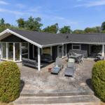 Ein Haus mit Terrasse, Gartenmöbeln und Grillplatz. Umgeben von Bäumen und Sträuchern.