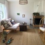 Wohnzimmer mit Sofa, Kamin und Pflanzen. Holzfußboden und Teppichboden.