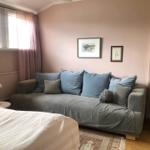 Ein Raum mit Sofa, Bett, Fenster und Wandbildern.